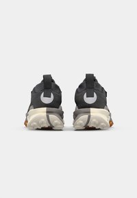 Baskets de sport noires et grises avec une tige texturée, un onglet de tirage au talon proéminent et des accents de logo blancs au dos. Semelle en caoutchouc avec un motif de semelle.