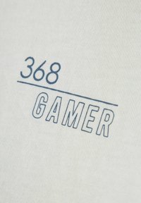 Camiseta de algodón blanca con un estampado gráfico azul que dice "368" sobre una línea horizontal y "GAMER" en letras mayúsculas y en negrita.