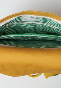 Borsa in tela gialla con un interno a strisce verdi, dotata di una tasca con zip e una finitura testurizzata. Include una tracolla beige per il trasporto.