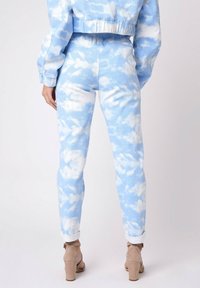 Conjunto de denim azul cielo que incluye una chaqueta corta y pantalones ajustados con un patrón de nubes. Los pantalones tienen dobladillos enrollados y una textura suave.