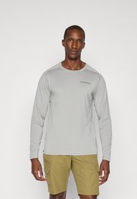 Light gray long-sleeve shirt with a round neck and subtle stitching, paired with olive green cargo shorts featuring multiple pockets.
