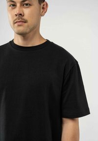 Zwarte katoenen t-shirt met een ronde halslijn en korte mouwen. De stof heeft een soepele textuur en een ontspannen pasvorm.