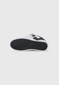Kõrge top sneaker, millel on valge nahkpealne, must kummitald, suur must logo ja tähdesign külgedel, tekstureeritud talla muster.