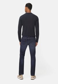 Chemise à manches longues bleu foncé associée à un jean en denim foncé. La chemise a un col rond et le jean présente un style classique à cinq poches.