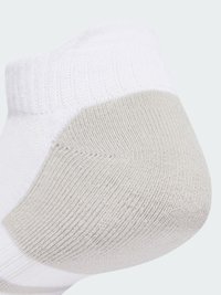 Biela členková ponožka so štruktúrovaným sivým pätičkou, s rebrovaným manžetom a hladkým telom. Jednoduchý dizajn zameraný na materiál a funkčnosť.
