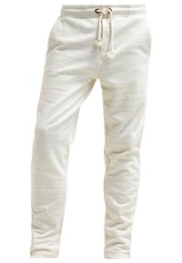 Ljust grå träningsbyxor med strukturerad textil, smal passform, elastisk midja och justerbar dragsko. Har subtila ljusa ränder.