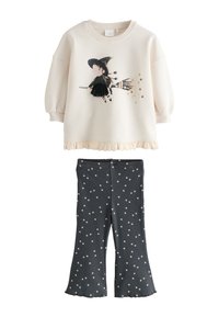 Sweatshirt crème clair avec graphique de sorcière, ourlet festonné ; leggings bleu marine avec motif d'étoiles blanches, texture côtelée, bas évasé.