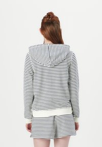 Sweat à capuche à rayures en blanc et marine, avec une coupe décontractée, des poignets côtelés et une poche kangourou à l'avant. Matière en mélange de coton lisse.