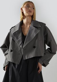 Lyhyt harmaa takki, jossa on suuri kaulus, kaksiriviset napit ja sivutaskut. Valmistettu silkkisestä materiaalista, jossa on kevyt kiilto.