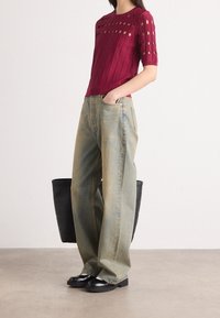 Burgundy neulepaita, jossa on aukollinen muotoilu ja ribbitekstuuri, yhdistettynä löysiin vaaleansinisiin farkkuihin ja mustiin platform-korkokenkiin. Musta olkalaukku l�ähellä.