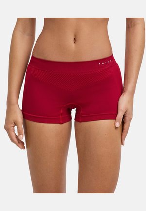 La zona centrale di una donna che indossa biancheria intima stile boxer rossa senza cuciture con un sottile motivo a chevron e il logo Falke sulla fascia in vita.