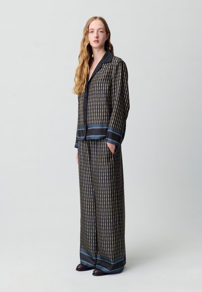 Set di pigiama nero a fantasia con design a catena dorata, composto da una camicia con bottoni, pantaloni larghi e dettagli in satin blu attorno ai polsini e all'orlo.