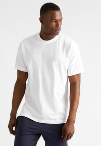 Witte katoenen T-shirt met korte mouwen en een klassieke ronde hals. Gladde textuur, eenvoudig ontwerp, geschikt voor casual gebruik.