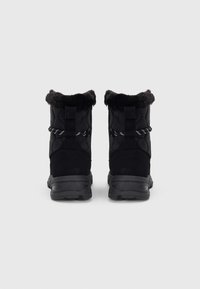 Pair of black winter boots with fur lining, sturdy soles, and reflective laces, shown from the back on a plain gray background.
