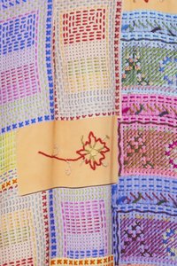 Tissu en patchwork multicolore avec une broderie complexe. Comprend des carrés de bleu, rose, vert et rouge, avec un motif de feuille au centre.