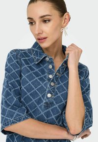 Jeans košulja s dijamantnim uzorkom, kratkim zavrnutim rukavima, dugmetima na preši u srebrnoj boji i klasičnim ovratnikom u srednje plavoj nijansi.