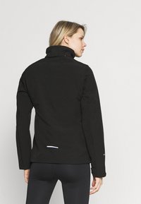 Zwarte waterdichte jas met een hoge kraag, lange mouwen en een reflecterende witte detail aan de achterzoom. Gladde, matte textuur.