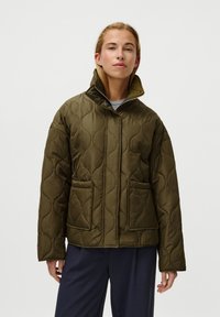 Jaqueta acolchoada verde-oliva com um colarinho alto, dois bolsos frontais e fecho éclair na frente. Textura suave com um padrão subtil.