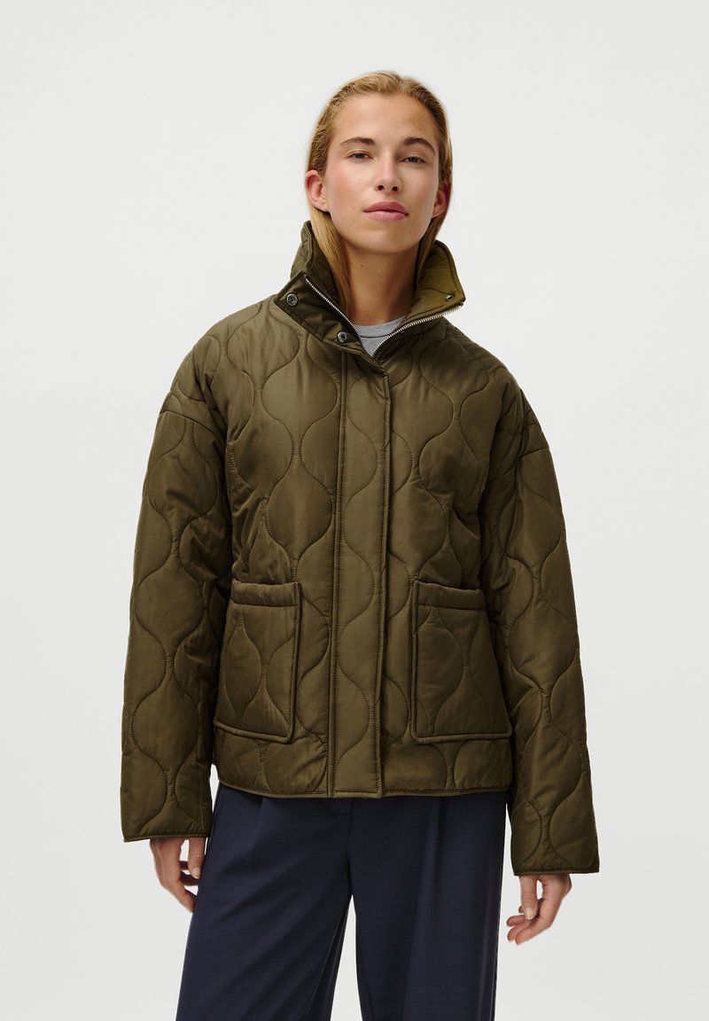 Jaqueta acolchoada verde-oliva com um colarinho alto, dois bolsos frontais e fecho éclair na frente. Textura suave com um padrão subtil.