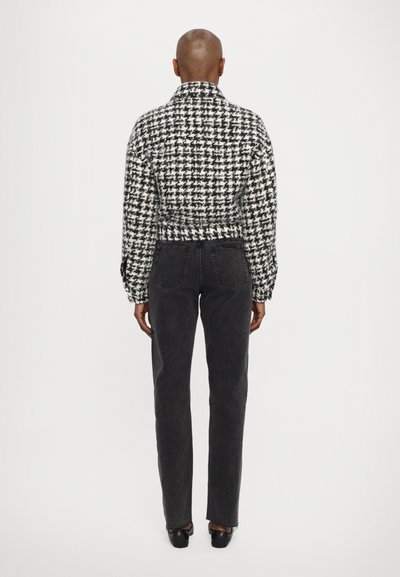 Melnā un baltā houndstooth rakstā veidota īsā jaka ar garām piedurknēm. Saskaņota ar augsto jostas līmeni melnām biksēm un melnām kurpēm.