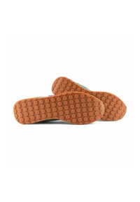Sneakers met een rubberen oranje zool met hexagonale patronen, groene bovenkant en een trekband aan de hiel.