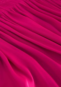 Fuchsia tyg med mjuka veck, med en smidig textur och enhetlig färg genom hela tyget. Designen visar en flödande utseende.