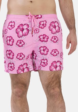Mann trägt pinke Badeshorts mit leuchtend pinken Hibiskusblumenmustern und vorderer Zugkordel.