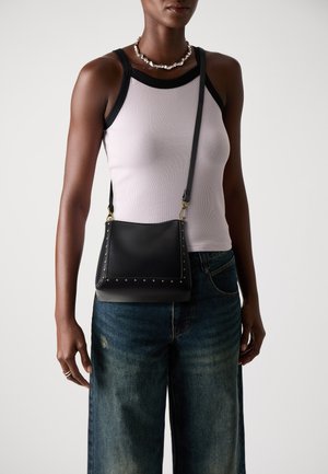 Sac en bandoulière en cuir noir avec des clous dorés sur le bord, doté d'un design plat et d'une sangle ajustable. S'associe avec un denim décontracté.
