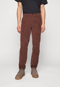 Bruna kordfluffbyxor med rak passform, med knappstängning, framfickor och en mjuk textur. Bärs med gråa desertboots.