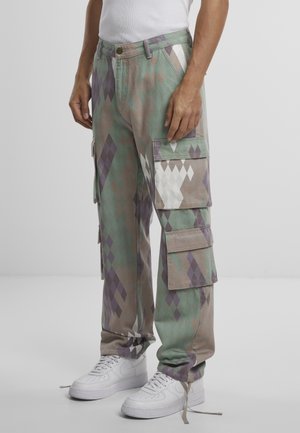 Cargo pants featuring a cotton blend with a green and purple diamond pattern, side pockets, and a relaxed fit, paired with white sneakers.