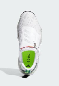 Vit sportskor med en texturerad ovandel, som har dragkedjestängning, grön innersula med etiketten "BOOST" och en fläckig grå sula.