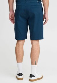 Shorts bleumarin din țesătură de bumbac, cu croi clasic, două buzunare la spate și o suprafață netedă. Purtați cu șosete albe și pantofi sport.