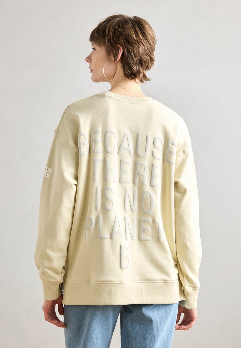 Felpa gialla chiaro con vestibilità oversize, caratterizzata da testo in rilievo sul retro: "PERCHÉ NON ESISTE UN PIANETA B." Materiale misto cotone.