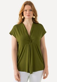 Olivově zelená blůza s hlubokým výstřihem ve tvaru V a uzlovým detailem na přední straně, krátké rukávy a splývavý střih, vyrobená z lehkého materiálu.