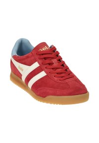 Zapatilla de ante roja con interior azul claro, con franjas laterales blancas y letras doradas. Suela de goma con patrón texturizado.