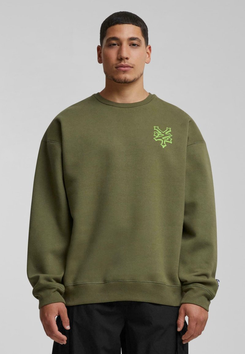 Olijfgroen sweatshirt van stevige katoen, met een ronde hals, ribgebreide manchetten en een groene geborduurde graphic op de linkerborst.
