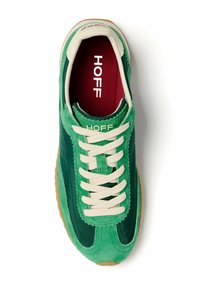 Zapatilla de ante verde con cordones crema, rayas en un verde oscuro que contrastan, suela de goma marrón y una plantilla roja con la palabra "HOFF."