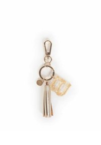 Portachiavi in pelle dorata e crema con un nappa, un charm a forma di lettera 'B' dorata e un'etichetta metallica rotonda attaccata a un moschettone.
