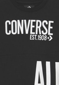 Felpa nera con testo bianco audace "CONVERSE EST. 1908" e "ALL" sul davanti. Girocollo e tessuto strutturato con finitura uniforme e liscia.