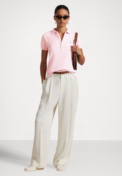 Rožinės spalvos polo marškinėliai su apykakle ir sagų juosta, derinami su kreminės spalvos plačiomis kelnėmis. Aksesuarai: rudas diržas ir rankinė.