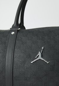 Borsa da viaggio nera con esterno testurizzato caratterizzato da un motivo stampato "23", hardware argento e un accento prominente del logo Jumpman argento.