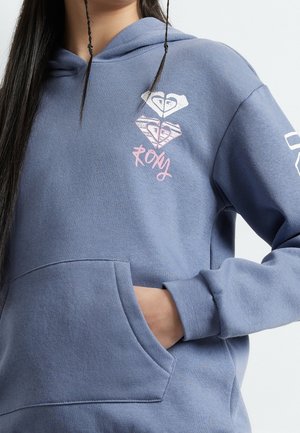 Felpa con cappuccio blu con tasca frontale, cappuccio con coulisse e stampe a forma di cuore con la scritta "Roxy". Tessuto morbido e vestibilità casual.