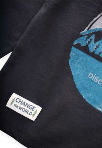Čierne bavlnené tričko s modrou grafikou hory a textom "DISCover." Obsahuje tkanú nášivku s textom "CHANGE the WORLD."