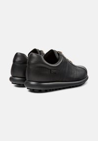 Pair of black leather casual sneakers with rounded rubber soles and beige laces, viewed from back and side on white background.