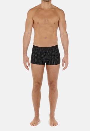 Boxer briefs neri con pois bianchi, elastico in vita e design aderente. Il tessuto appare liscio ed elastico. Il modello è in piedi a piedi nudi.