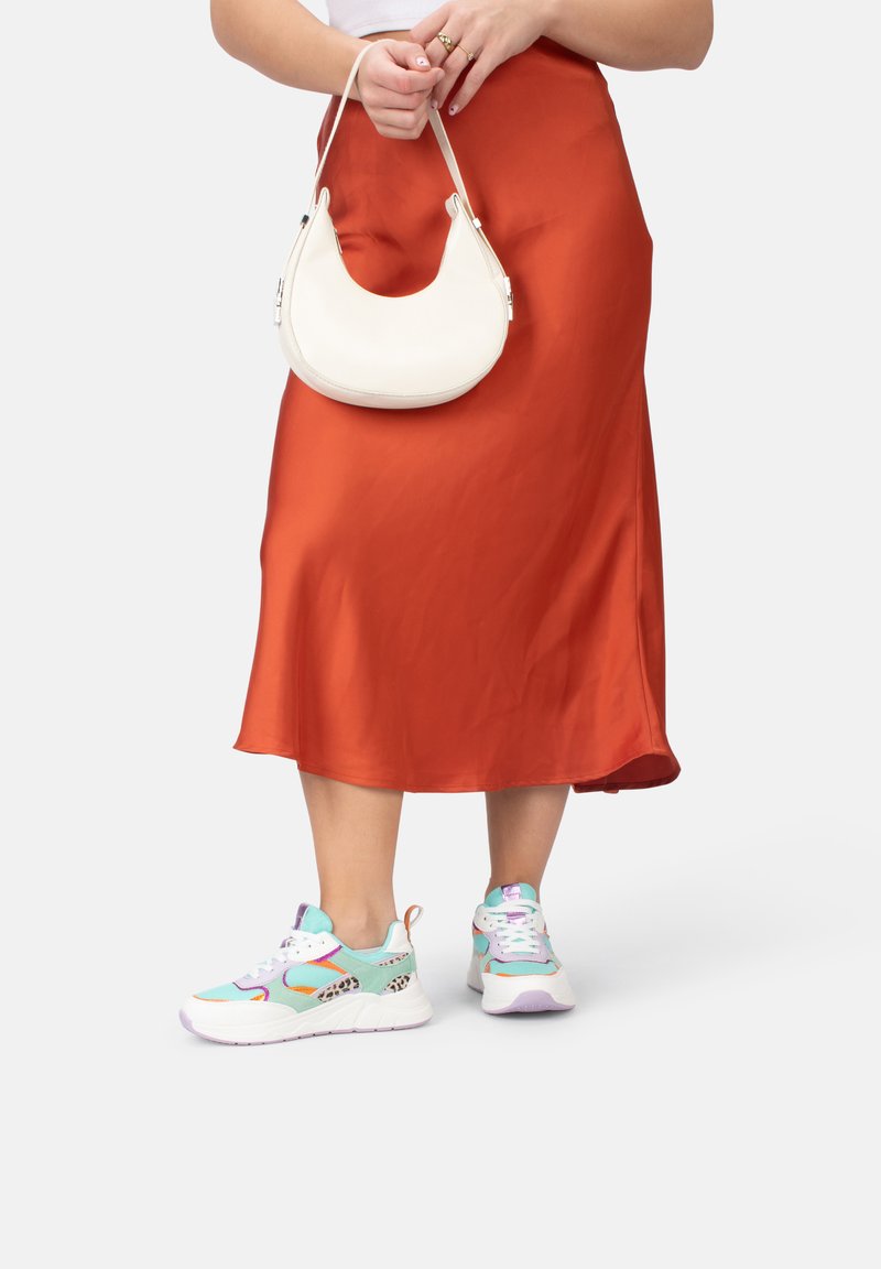 Bunt gefärbte Sportsneaker aus weichem Material mit weißer Sohle und dezentem Leopardenmuster, kombiniert mit einem seidigen orangen Rock und einer weißen Handtasche.