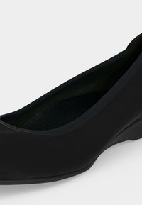 Chaussure femme noire à petit talon, bout arrondi et finition lisse, vue de profil avant sur fond blanc.