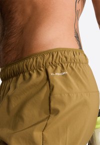 Khaki shorts in lightweight fabric with an elastic waistband. Features include FLASHDRY logo and a side pocket detail.