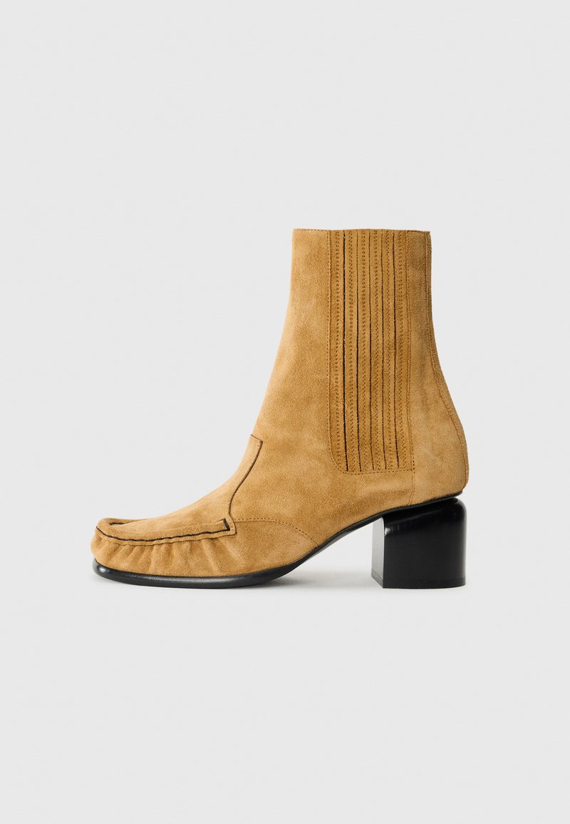 Bottines en cuir suédé jaune moutarde avec un bout arrondi, un panneau latéral texturé et un talon bloc noir épais.