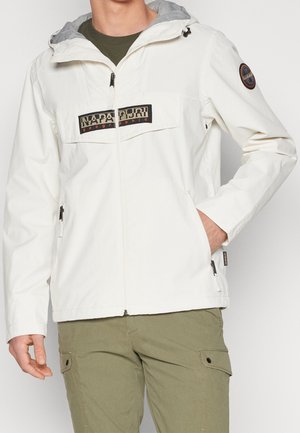 Chaqueta ligera blanca con capucha gris, que presenta un parche de logo negro en el pecho, bolsillos laterales con cremallera y un cierre frontal con cremallera.